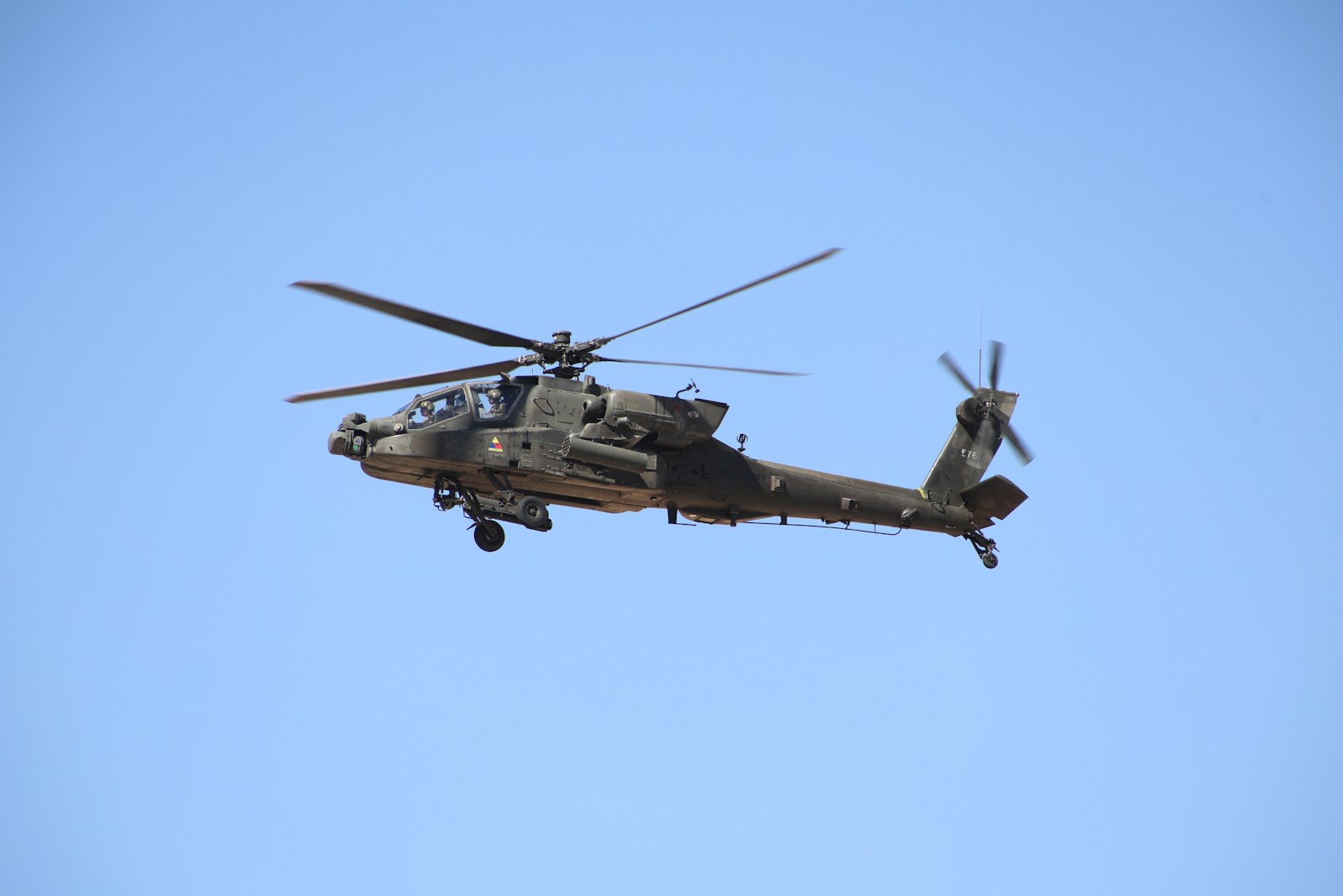 A military helicopter flying through a blue sky