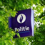 Police station sign visible through leafy branches.