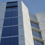 A tall white building with blue windows against a blue sky