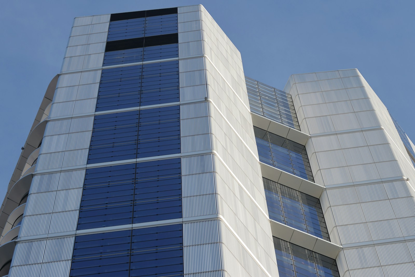 A tall white building with blue windows against a blue sky