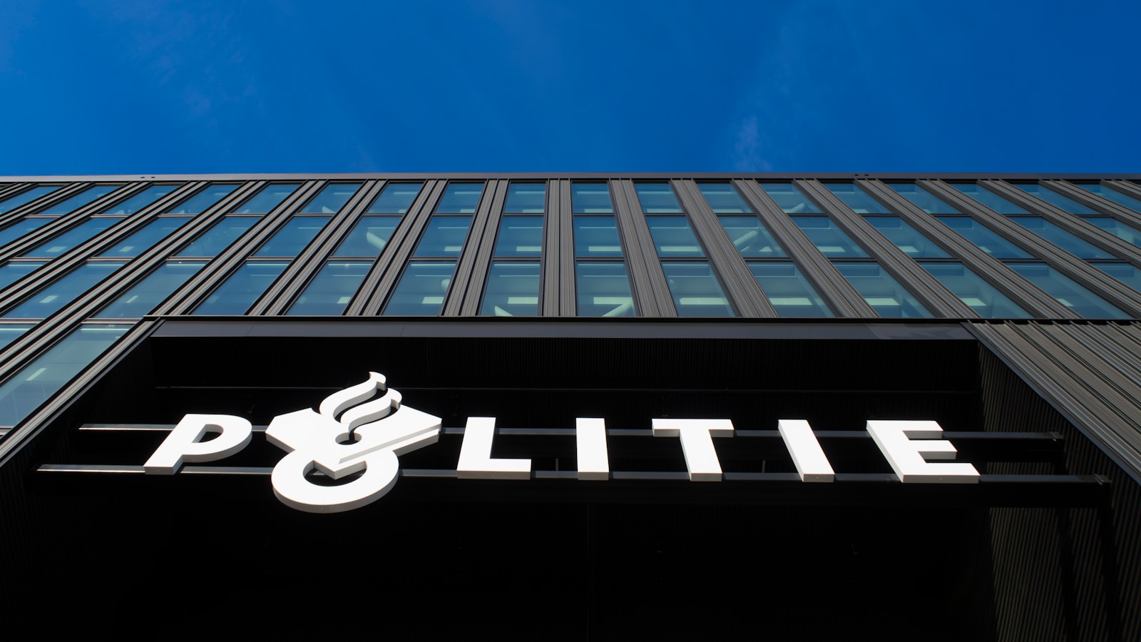 Modern building with "politie" sign under blue sky