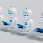 a group of white robots sitting on top of laptops