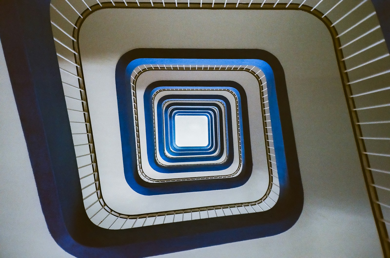 Looking down a modern spiral staircase with blue accents.