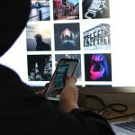 person holding black smartphone near black computer keyboard