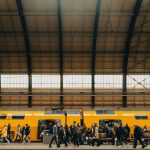 a group of people walking next to a yellow train