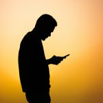 a silhouette of a man using a cell phone